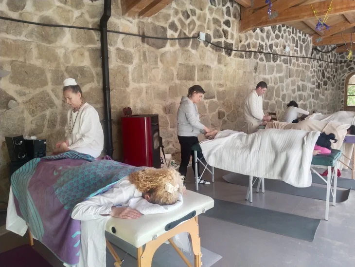 Alumnos practicando masaje yóguico por parejas durante un retiro en una sala de piedra