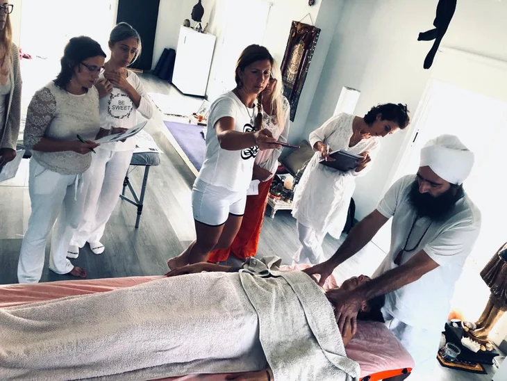 Grupo de alumnas practicando masaje yóguico mientras Lakhmi Chand demuestra un tratamiento